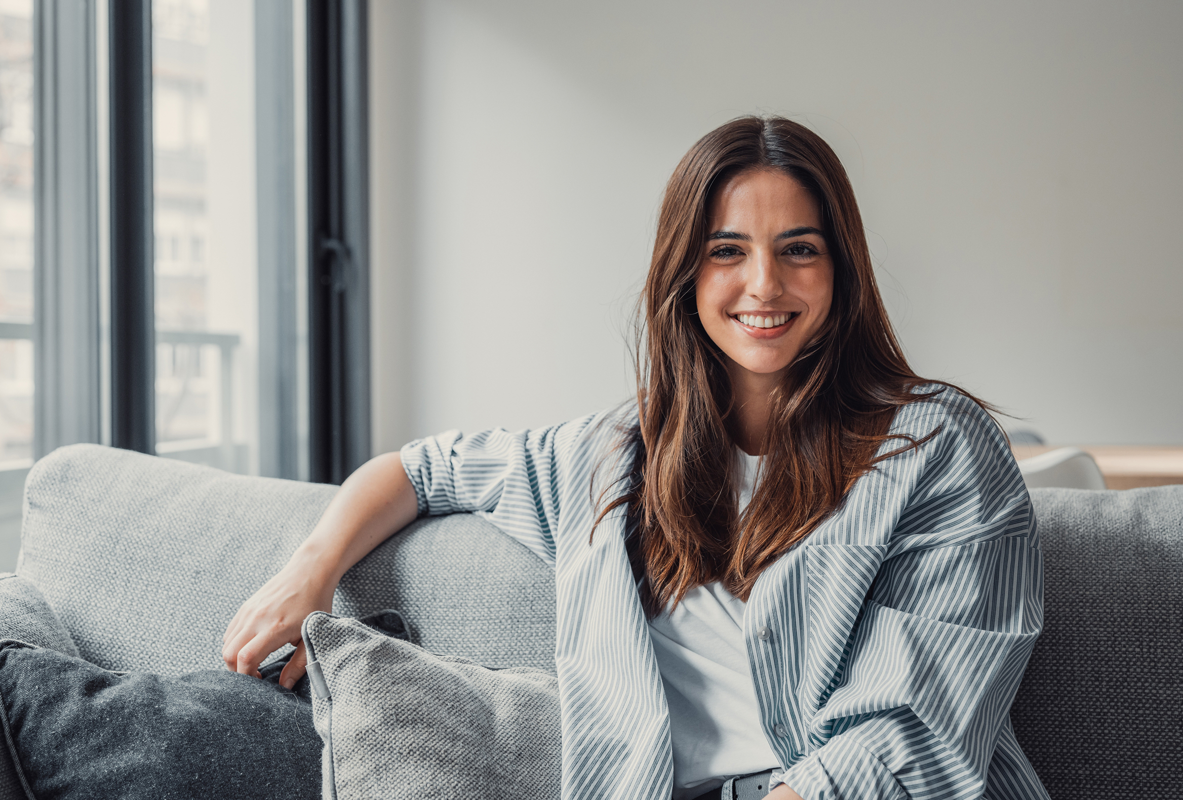 Profissional da saúde sorrindo sentada em um sofá
